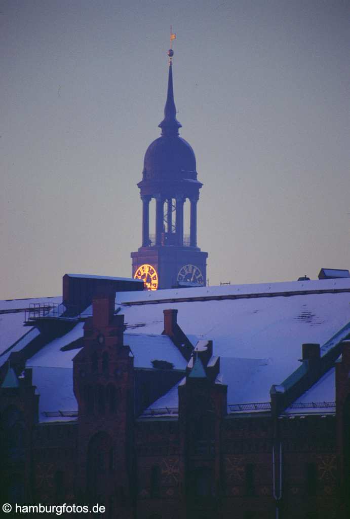 mi050 St. Michaelis das Wahrzeichen von Hamburg sowie Hauptkirche. Turmspitze des Michels mit schneebedeckten Daechern der Speicherstadt.