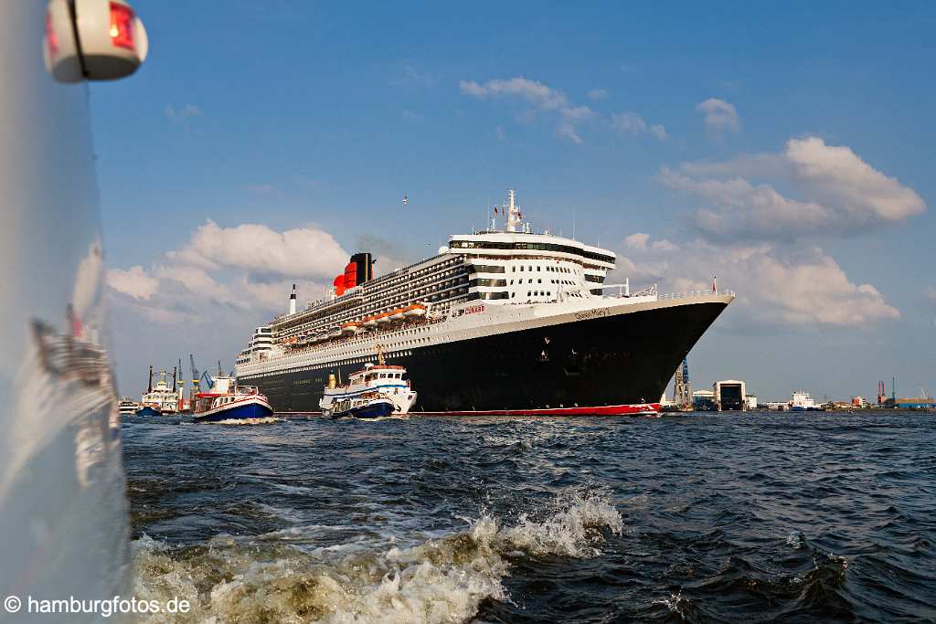 bz0447 Das Kreuzfahrtschiff "Queen Mary 2" laeuft aus dem Hamburger Hafen aus, zahlreiche kleine Schiffe begleiten den Luxusliner. An Deck stehen winkende Passagiere, sonnig