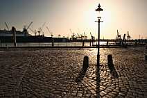bz00001 Blick vom Hamburger Fischmarkt mit historischer Strassenlaterne auf ein im Dock bei Blohm & Voss liegendes Kreuzfahrtschiff, sonniges Gegenlicht