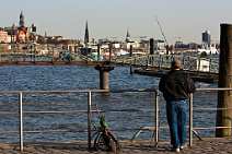 bz00127 Angler steht auf einer Brücke am Fisschmarkt und angelt in der Elbe vor sonniger Hamburg-Kulisse