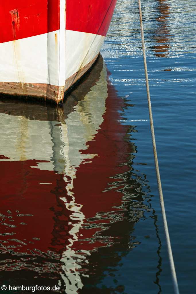 bz00666 Rot-weisser Schiffsbug spiegelt sich im Wasser des Hafenbeckens von List/Sylt, sonnig